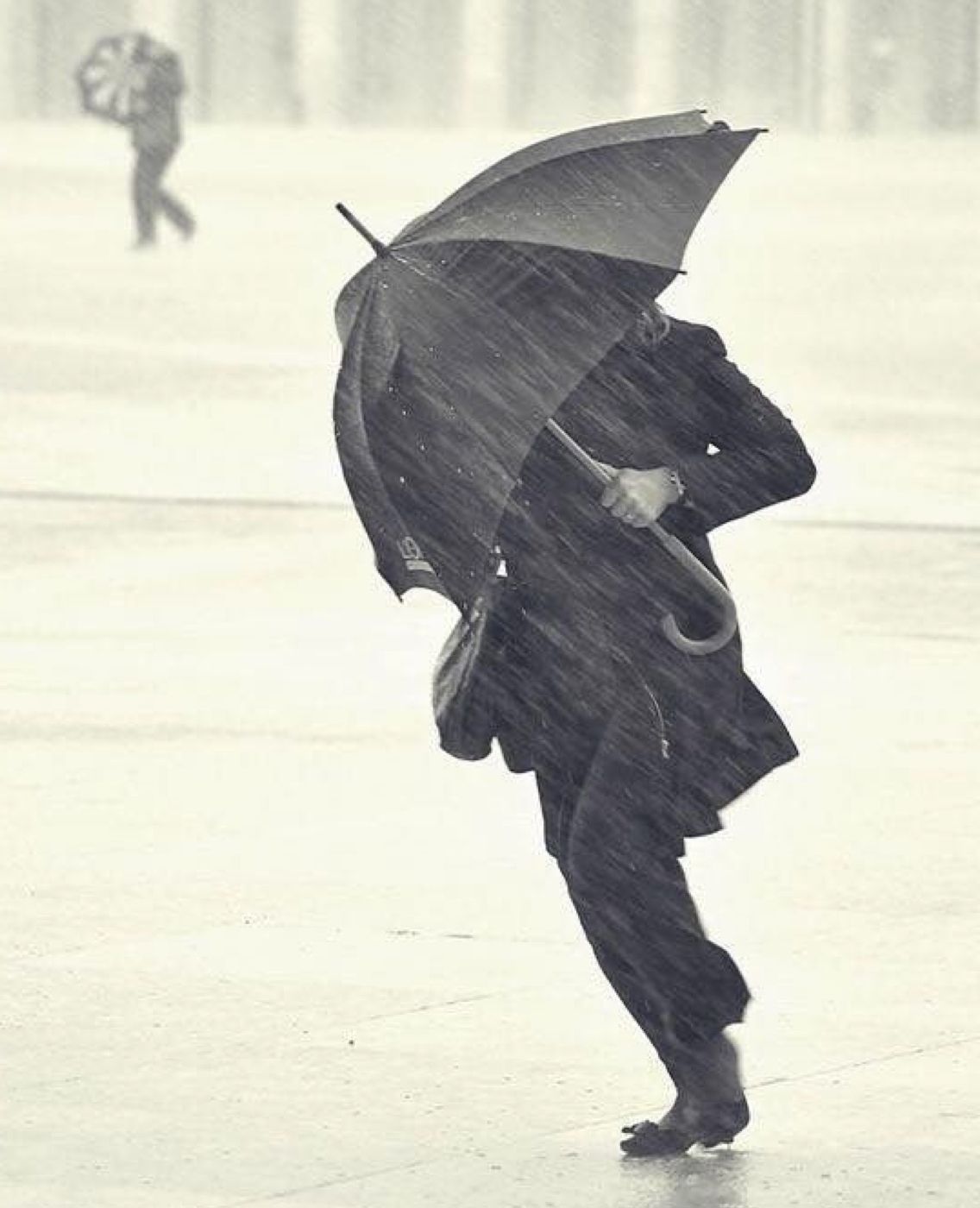 A person holding an umbrella in heavy rain